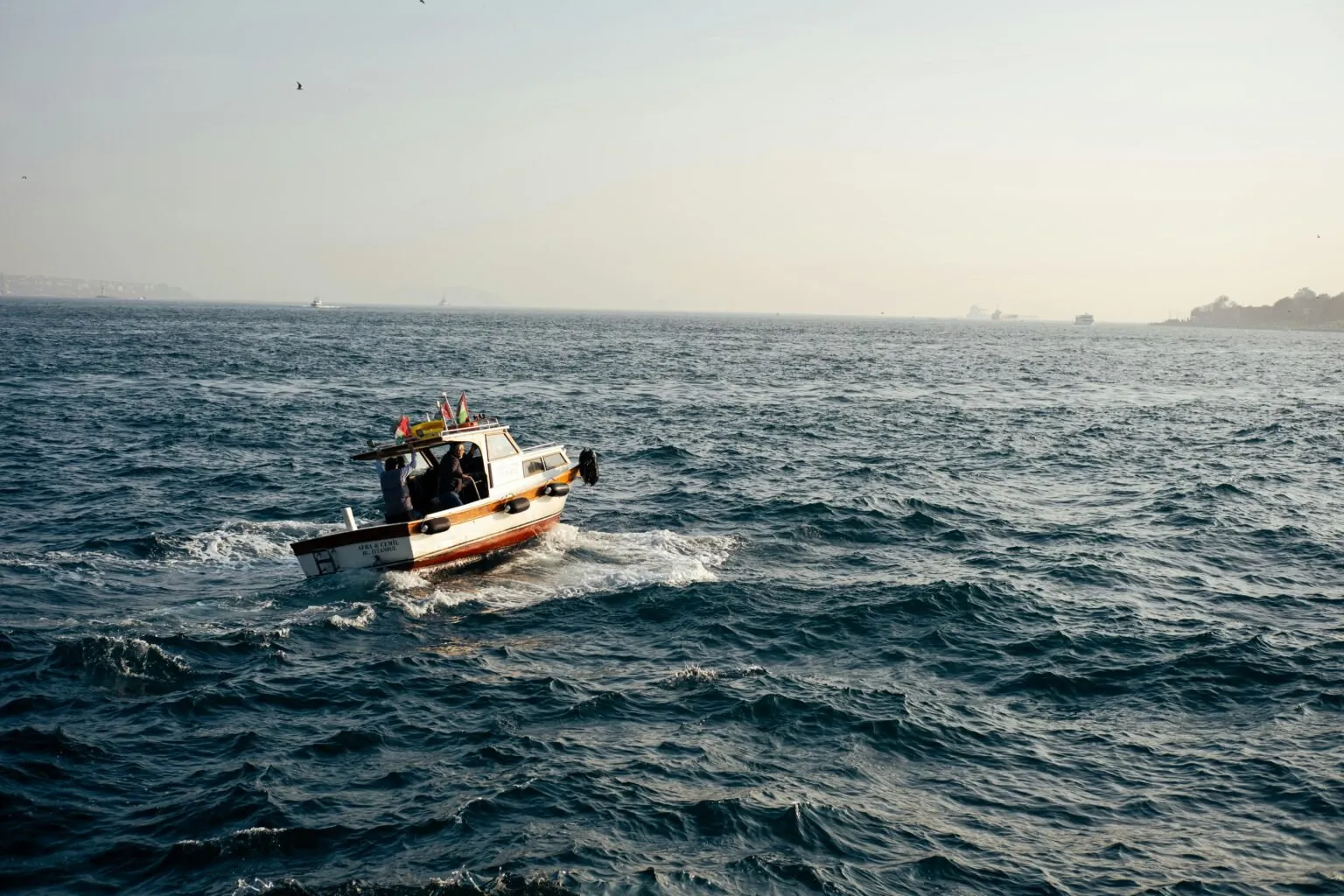 A small fishing boat sails on a calm sea under a clear sky.