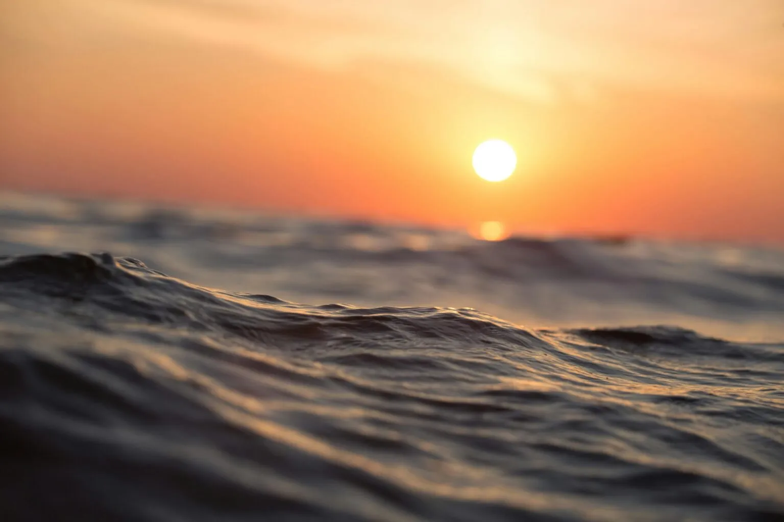 Ocean waves with a vibrant sunset sky.